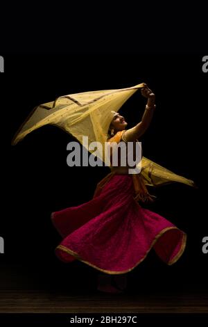 Kathak Tänzerin kreist anmutig während einer Performance vor einem dunklen Hintergrund. Stockfoto