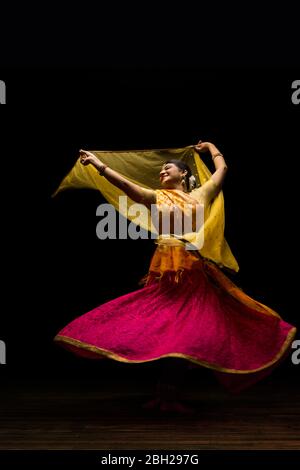 Kathak Tänzerin kreist anmutig während einer Performance vor einem dunklen Hintergrund. Stockfoto