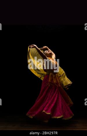 Kathak Tänzerin kreist anmutig während einer Performance vor einem dunklen Hintergrund. Stockfoto