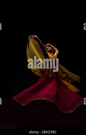 Kathak Tänzerin kreist anmutig während einer Performance vor einem dunklen Hintergrund. Stockfoto