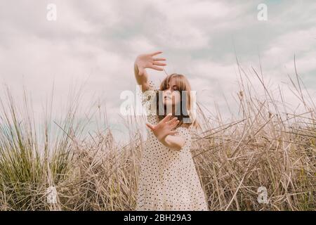 Frau im Vintage-Kleid allein auf einem abgelegenen Feld in der Landschaft zu erreichen Stockfoto