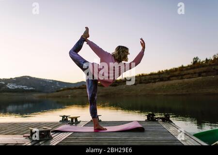 Junge Frau, die Yoga auf einem Steg macht, Tänzerposition Stockfoto