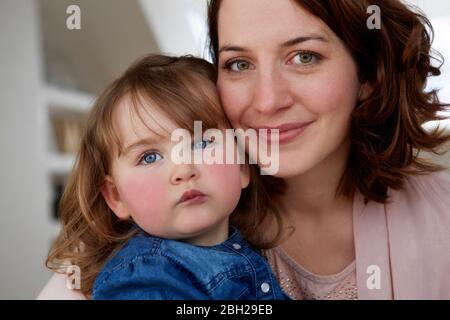 Porträt einer glücklichen jungen Mutter Kopf an Kopf mit ihrer kleinen Tochter Stockfoto