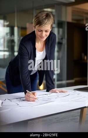 Frau, die im Büro an einem Bauplan arbeitet Stockfoto