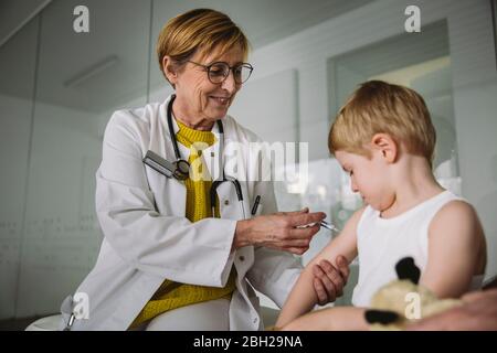 Kinderarzt injiziert Impfstoff in den Arm des Kleinkindes Stockfoto