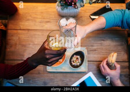 Zwei Personen sitzen im Restaurant, essen und trinken, mit digitalem Tablet auf dem Tisch Stockfoto