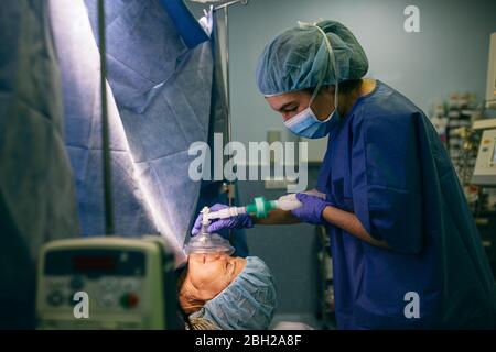 Anästhesist, der das Anästhesiesystem auf den Patienten im Operationssaal anwendet Stockfoto