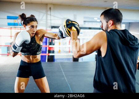 Boxershorts Sparring mit ihrem Trainer im Fitnessstudio Stockfoto