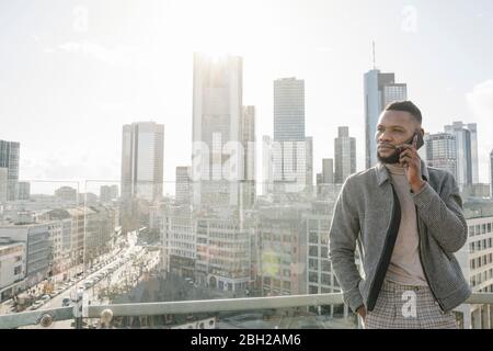 Stilvoller Mann am Telefon auf Aussichtsterrasse mit skycraper-Blick, Frankfurt, Deutschland Stockfoto