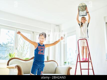 Junge und Mädchen spielen Basketball im Wohnzimmer Stockfoto