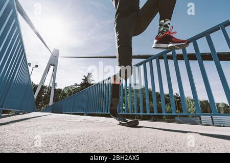 Niedriger Abschnitt des behinderten Athleten mit Beinprothese läuft auf einer Brücke Stockfoto