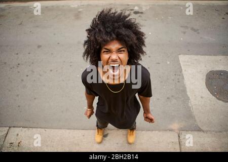 Porträt eines schreienden jungen Mannes mit Afro auf der Straße stehen Stockfoto