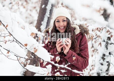 Porträt einer glücklichen jungen Frau mit heißem Getränk im Winter Stockfoto