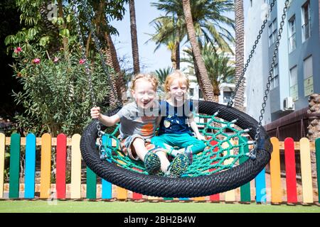 Porträt eines Jungen und seiner kleinen Schwester sitzen zusammen auf einer Schaukel, Spanien Stockfoto