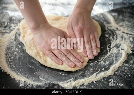 Hände der Frau kneten Teig auf der Arbeitsplatte, Nahaufnahme Stockfoto