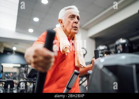 Älterer Mann, der im Fitnessstudio beim Stepper trainiert Stockfoto