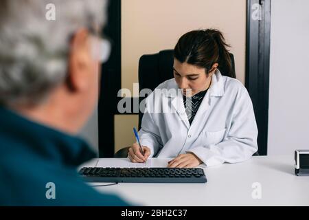 Arzt, der sich während einer Konsultation in der Praxis Notizen gemacht hat Stockfoto
