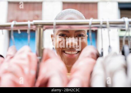 Porträt einer glücklichen Frau hinter Kleiderstange Stockfoto