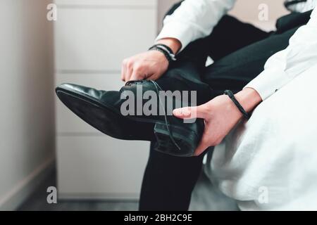 Junger Mann, der Schuhe an, auf dem Bett sitzend Stockfoto