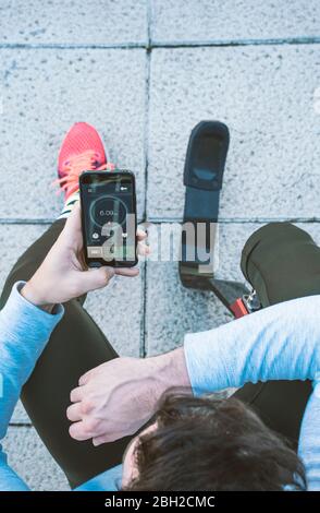 Behinderter Sportler mit Beinprothese eine Pause vom Training machen und Handy mit Daten überprüfen Stockfoto