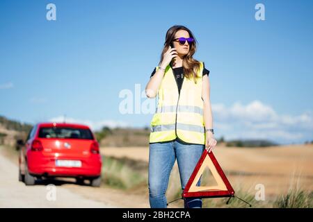 Frau, die auf dem Land eine Panne hat und telefoniert Stockfoto