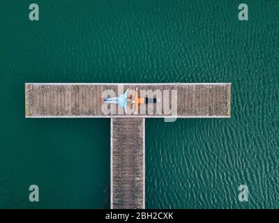 Zwei Frauen liegen auf dem Steg mit ausgestreckten Armen, Valdemurio Reservoir, Asturien, Spanien Stockfoto