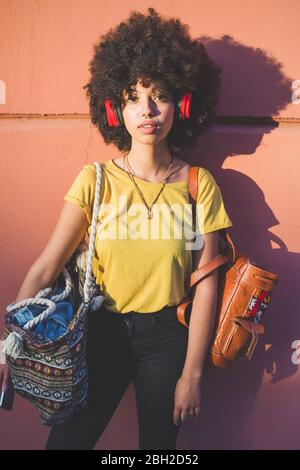 Portrait einer jungen Frau mit Afro-Frisur Musik hören mit Kopfhörern Stockfoto