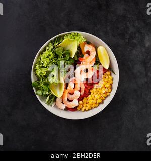 Schüssel mit frischem Mais, Tomaten, Zitrone, Garnelen, Mais-Salat, Zichorie und Lollo bionda Salat Stockfoto