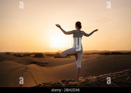 Frau, die Yoga in Sanddünen bei Sonnenuntergang praktiziert, Gran Canaria, Spanien Stockfoto