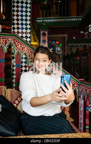 Porträt einer glücklichen jungen Frau in einem Teeladen, die Selfie mit dem Smartphone macht Stockfoto