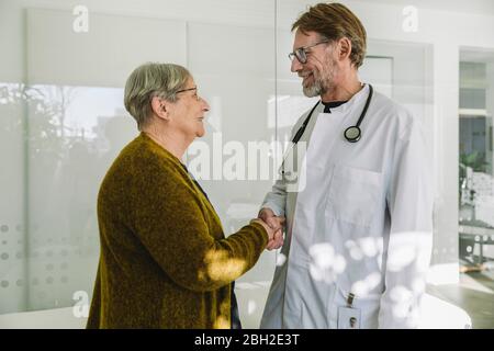 Arzt und Seniorpatient in der medizinischen Praxis Händeschütteln Stockfoto