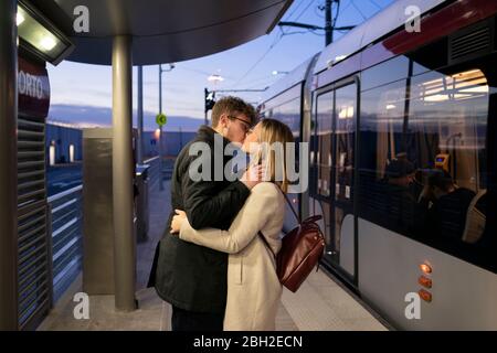 Küssen junges Paar an der Straßenbahnhaltestelle am Abend stehen Stockfoto