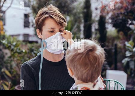 Littley Junge hilft seiner Mutter, eine Gesichtsmaske zu setzen Stockfoto