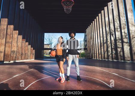 Porträt von jungen Mann und Frau auf dem Basketballplatz stehen Stockfoto