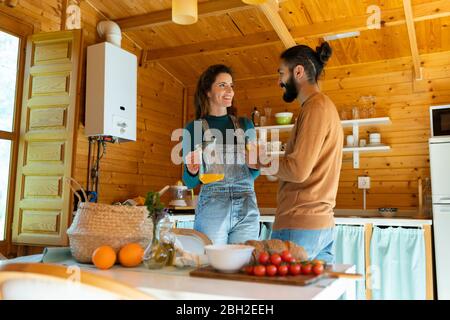 Junges Paar trinkt frischen Orangensaft in einer Holzhütte Stockfoto