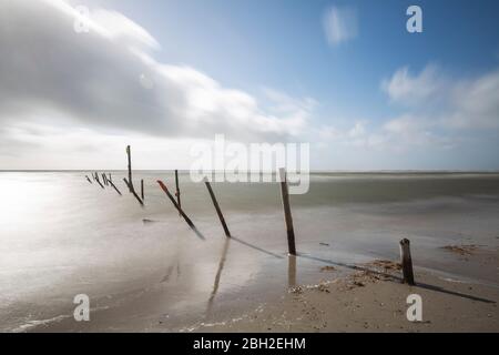 Dänemark, Romo, Blavand, lange Wolkenbelastung über Reihe von Küstenpolen Stockfoto