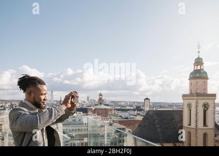 Stilvoller Mann auf der Aussichtsterrasse, der ein Handy-Foto macht, Frankfurt, Deutschland Stockfoto