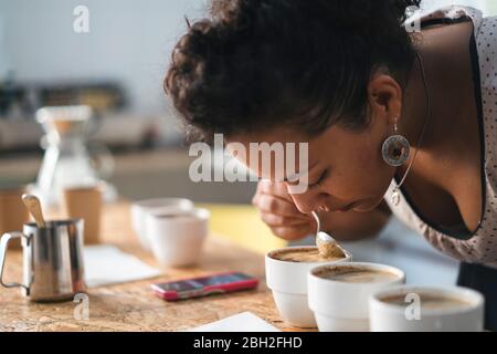 Frau, die in einer Kaffeerösterei arbeitet, die an einem Produkt riecht Stockfoto