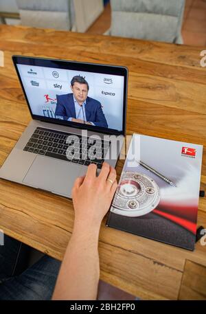 Warendorf, Deutschland. April 2020. Ein Mann schaut auf den Monitor seines Laptops, auf dem Christian Seifert, CEO und Sprecher des Vorstands der Deutschen Fußball-Liga (DFL), im Anschluss an die DFL-Hauptversammlung bei einer Live-Video-Pressekonferenz zu den Folgen der Corona-Pandemie zu sehen ist. Kredit: Guido Kirchner/dpa/Alamy Live News Stockfoto