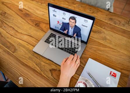 Warendorf, Deutschland. April 2020. Ein Mann schaut auf den Monitor seines Laptops, auf dem Christian Seifert, CEO und Sprecher des Vorstands der Deutschen Fußball-Liga (DFL), während einer Live-Video-Pressekonferenz nach der DFL-Hauptversammlung zu den Folgen der Corona-Pandemie zu sehen ist. Kredit: Guido Kirchner/dpa/Alamy Live News Stockfoto