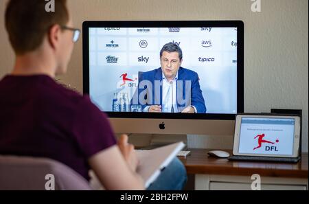 Warendorf, Deutschland. April 2020. Ein Mann schaut auf den Monitor seines Computers, auf dem Christian Seifert, CEO und Sprecher des Vorstands der Deutschen Fußball-Liga (DFL), während einer Live-Video-Pressekonferenz nach der DFL-Hauptversammlung zu den Folgen der Corona-Pandemie zu sehen ist. Kredit: Guido Kirchner/dpa/Alamy Live News Stockfoto