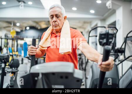 Älterer Mann, der im Fitnessstudio beim Stepper trainiert Stockfoto