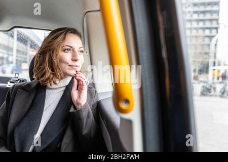 Frau im hinteren Teil eines Taxis, die aus dem Fenster schaute, London, Großbritannien Stockfoto