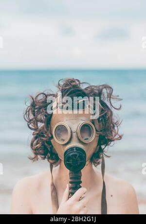 Junge Frau am Strand, mit Gasmaske Stockfoto