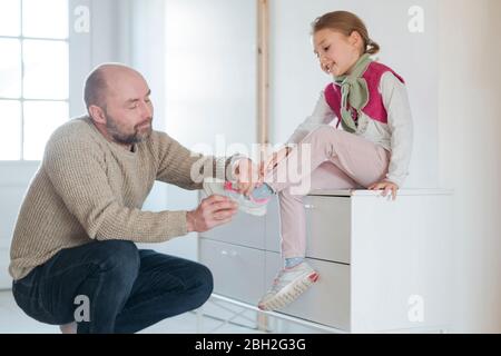 Vater hilft Tochter Schuhe zu Hause anziehen Stockfoto