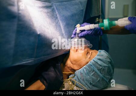 Anästhesist, der das Anästhesiesystem auf den Patienten im Operationssaal anwendet Stockfoto