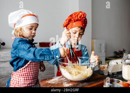 Bruder und Schwester bereiten Teig in der Küche zu Hause Stockfoto