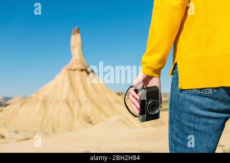 Frau mit einer Vintage-Kamera in der desertischen Landschaft von Bardenas Reales, Arguedas, Navarra, Spanien Stockfoto