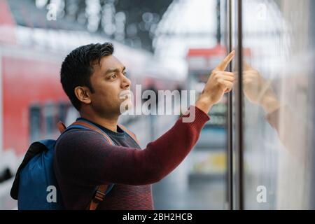 Mann, der den Fahrplan am Bahnhof überprüft Stockfoto