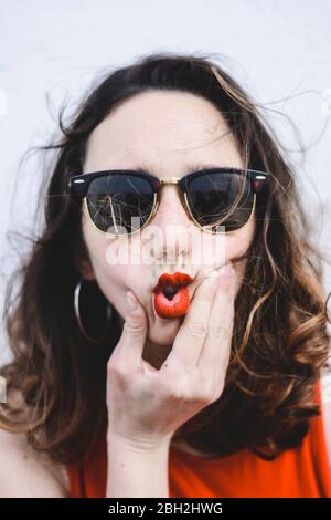 Porträt einer jungen Frau mit roten Lippen tragen Sonnenbrille pouting Mund Stockfoto